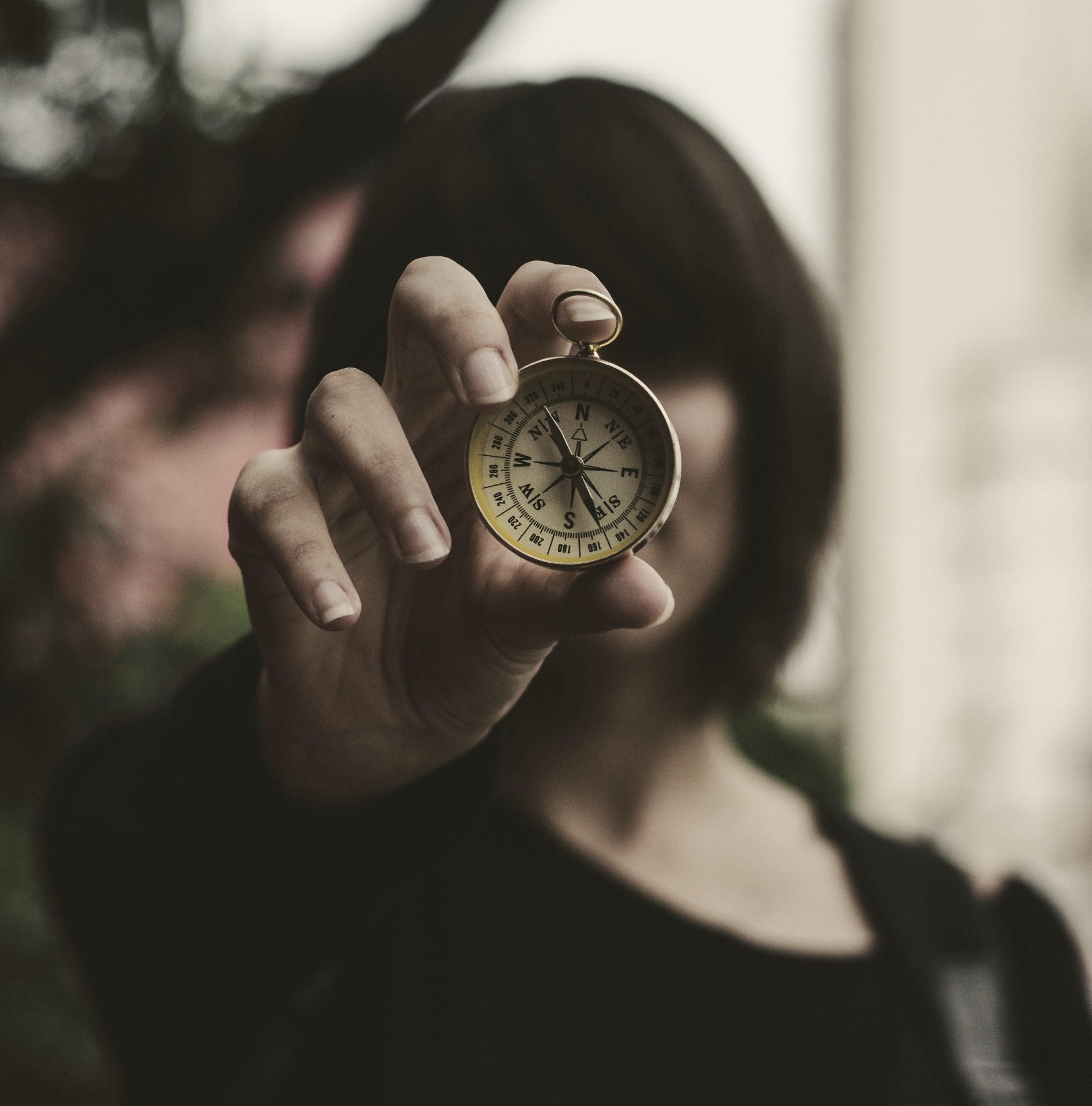 A brass compass and a softly folded map with a small wooden trail marker — a quiet image of orientation and wayfinding.